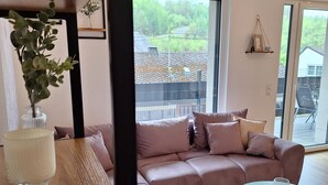 Ein modernes Wohnzimmer mit einer Eckcouch, einem Glastisch und einer Topfpflanze.