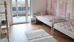 Ein Schlafzimmer mit Bett, Nachttisch, einem Regal mit Spielzeug, einem Fenster mit Blick und einer Wand mit Muster.