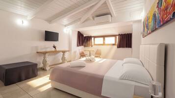 Habitación de hotel con cama, escritorio, silla, televisión y ventana con cortinas.