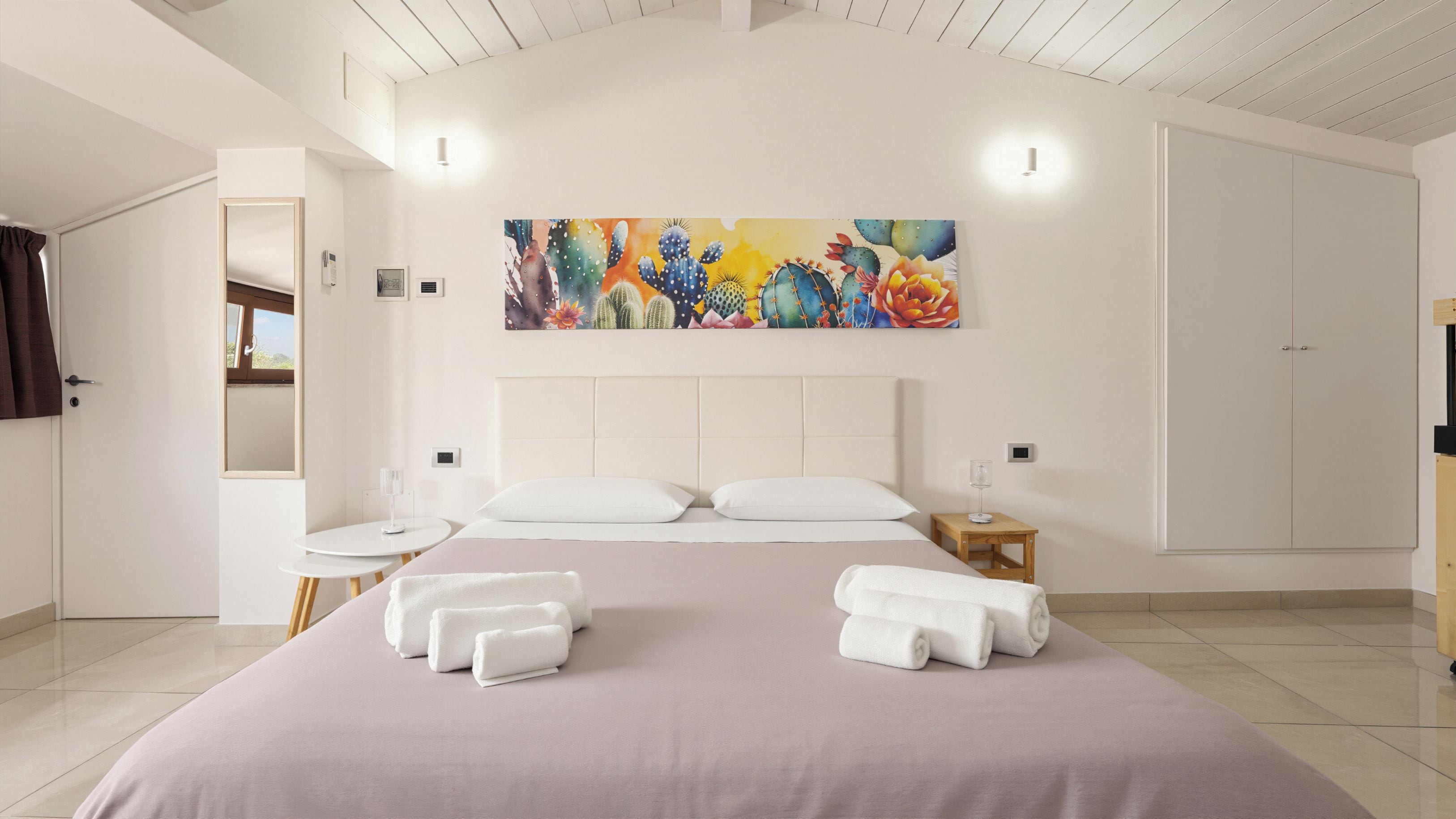 Una habitación de hotel con una cama grande, dos mesitas de noche, un cuadro en la pared y un armario.