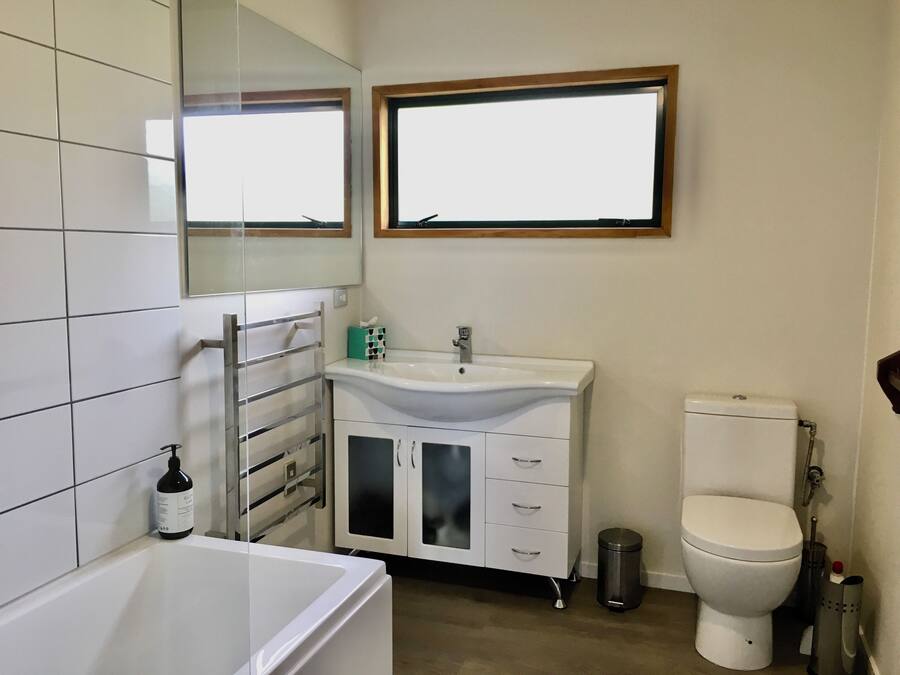 A bathroom with a bathtub, a sink, a toilet, and a mirror.