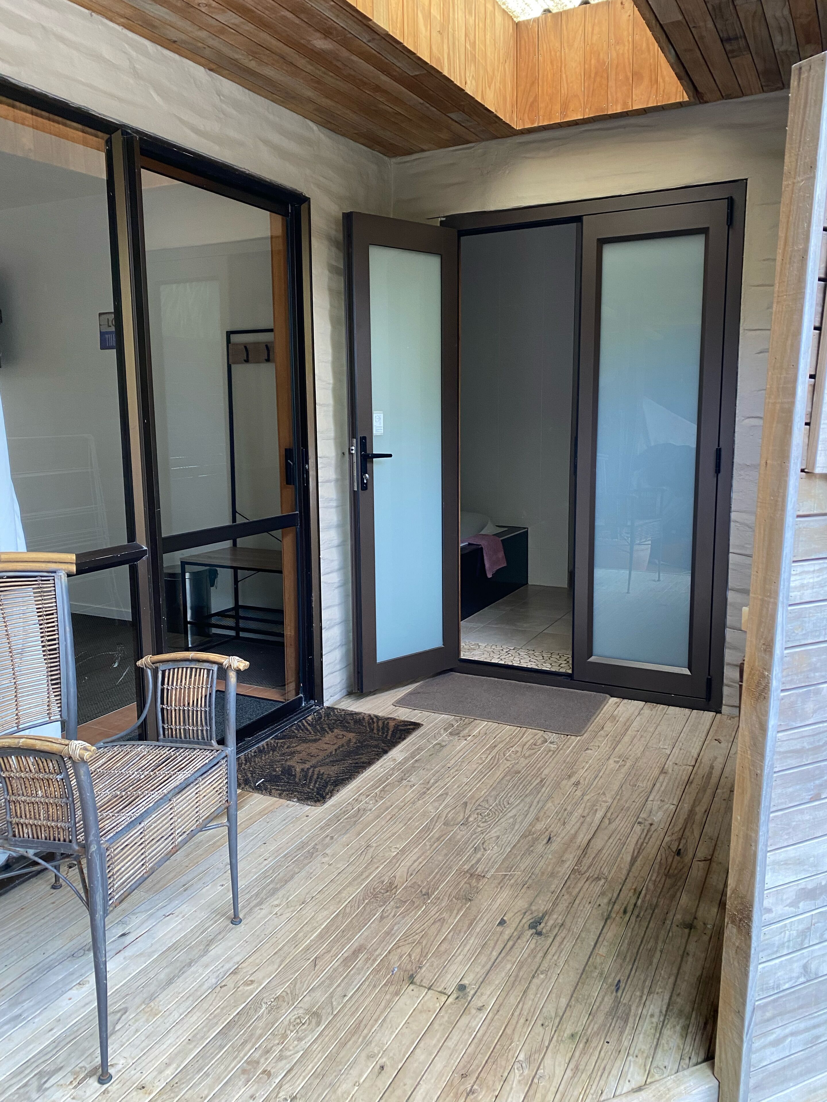 A room with a sliding glass door leading to a balcony, a wicker chair, and a wooden floor.