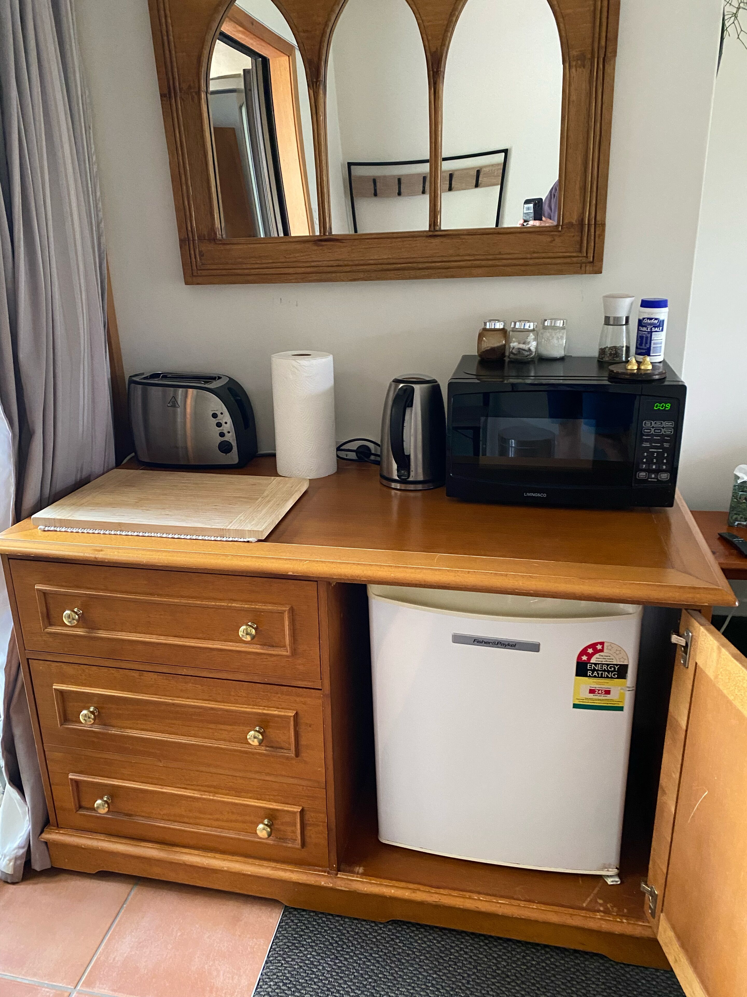 A compact kitchenette with a toaster, kettle, microwave, and a small refrigerator.