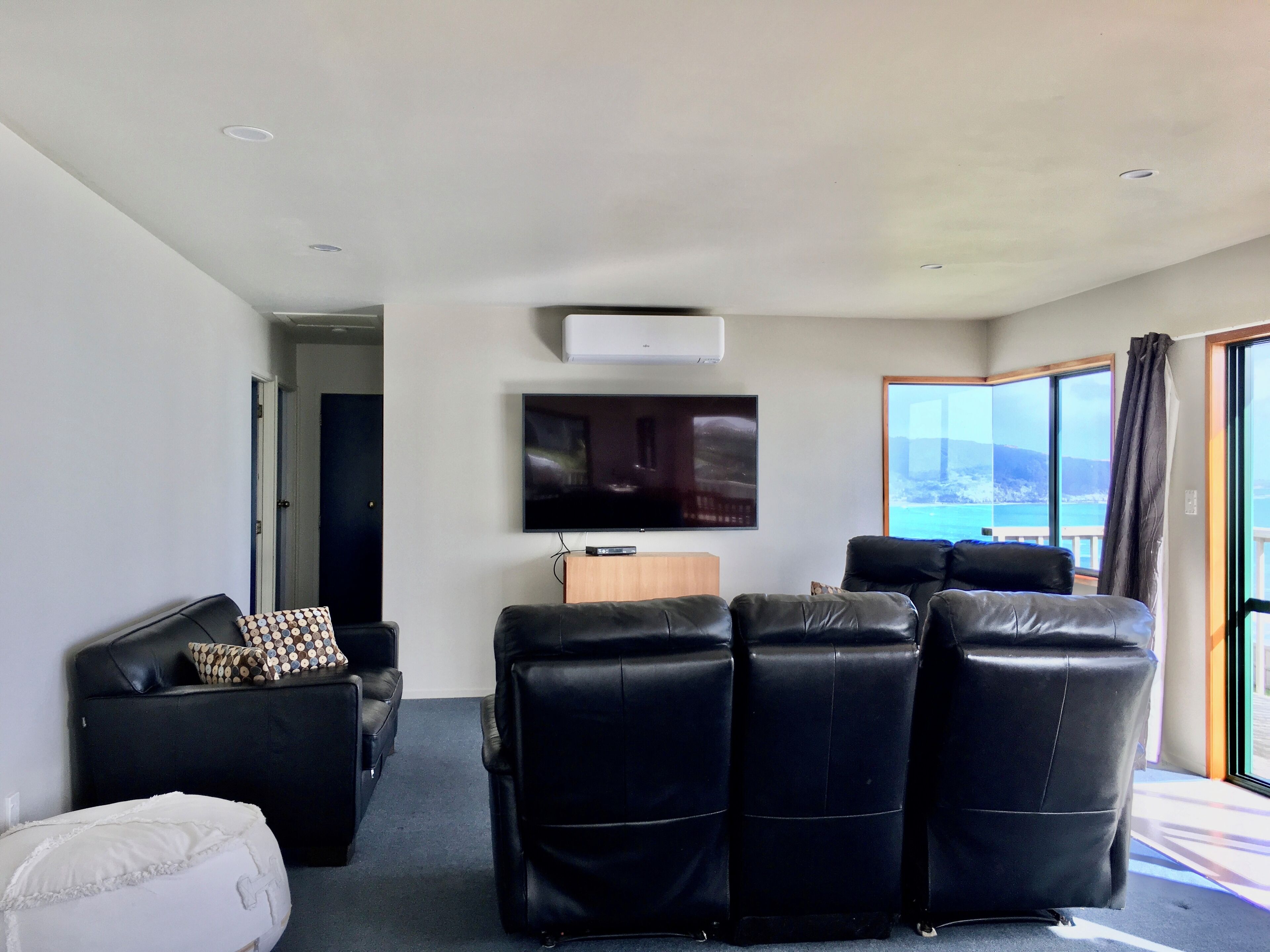 Una sala de estar moderna con un televisor de pantalla plana, un sofá y un gran ventanal con vistas panorámicas.
