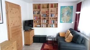 Una sala de estar con una estantería, un sofá, un televisor y un cuadro en la pared.