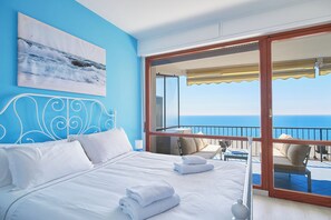 A bedroom with a large bed, a view of the ocean, and a balcony with outdoor seating. - I Gabbiani sul Mare (Cervo)