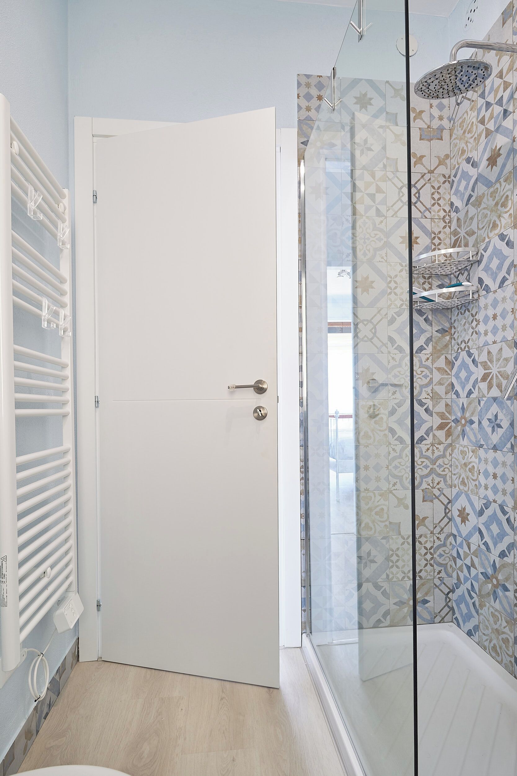 A bathroom with a shower, a glass door, and a tiled wall.