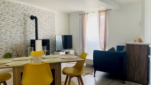 En moderne stue med spiseplads, fjernsyn og pejs.