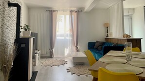 En moderne stue med spiseplads, med en sofa, et sofabord og et spisebord med gule stole og bordskåner.