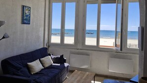 Un salon avec vue sur la plage, un canapé, une table basse et un téléviseur.