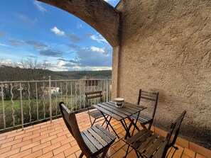 Enjoy a serene view of the surrounding landscape from this balcony, featuring a table and chair for outdoor dining.