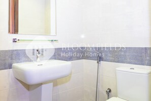Un bagno con un lavandino bianco, uno specchio e un water.