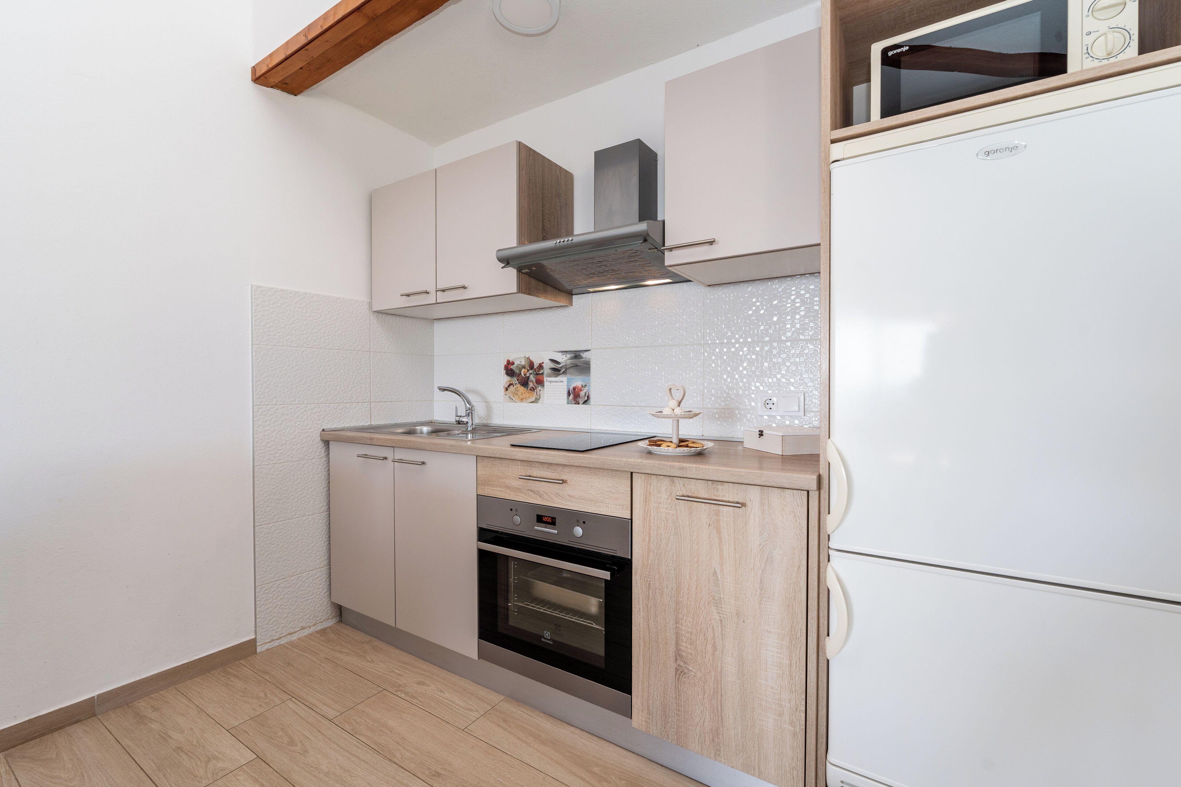Cocina compacta con horno integrado, microondas y campana extractora de acero inoxidable.