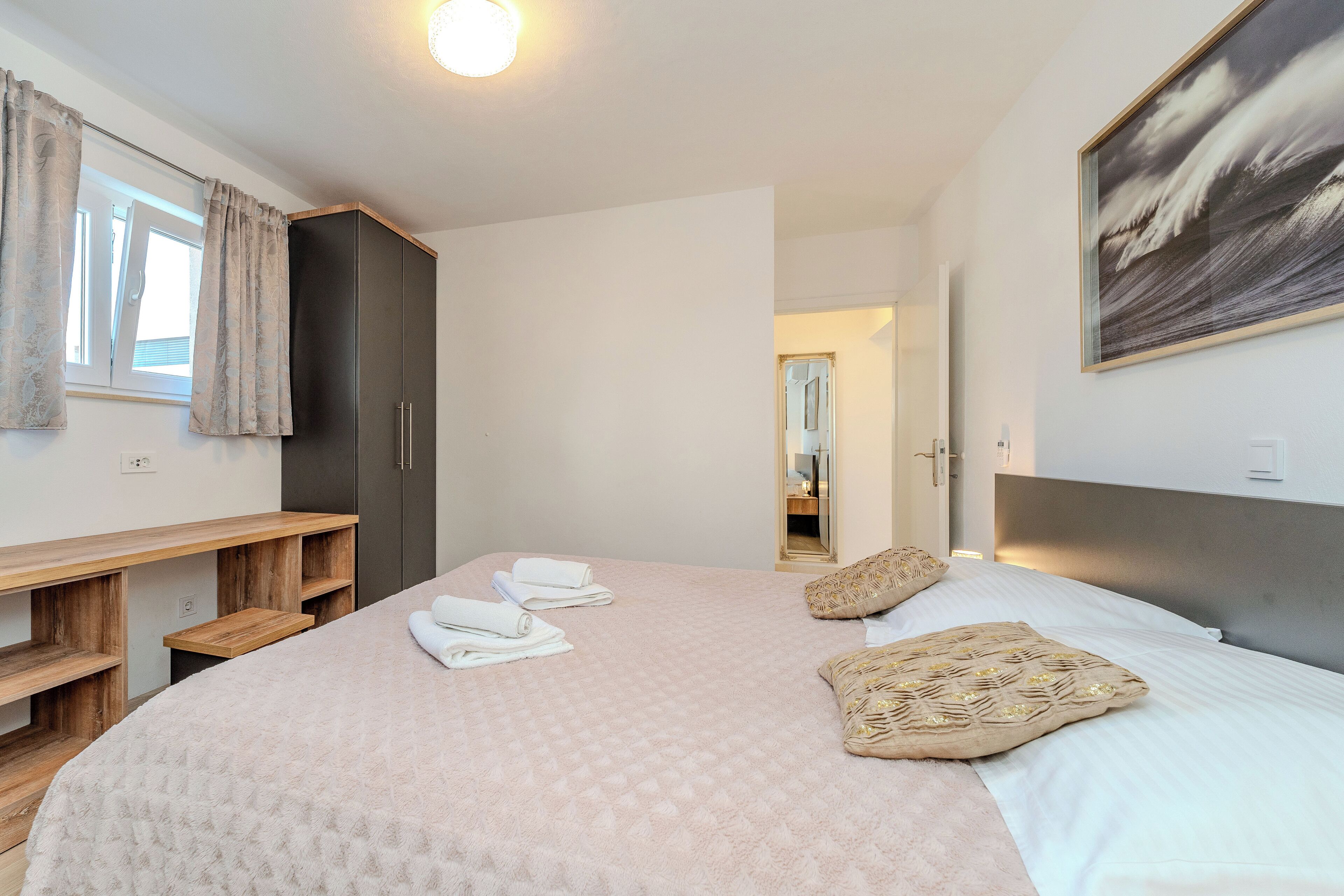 A bedroom with a large bed, a wooden desk, and a wardrobe.