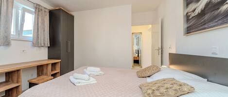 A bedroom with a large bed, a wooden desk, and a wardrobe.