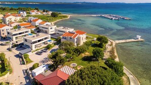A coastal residential area with modern buildings, clear blue waters, and a marina. - Apartments Batela  (Privlaka)