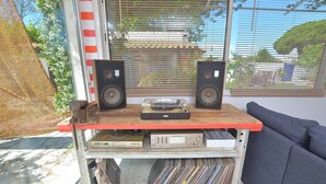 Una habitación con ventana, un sofá y una mesa con altavoces y un tocadiscos.