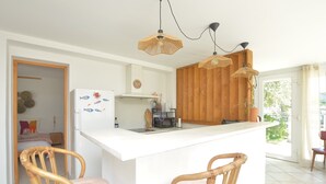 Una cocina con encimera blanca, armarios de madera y dos sillas de mimbre.