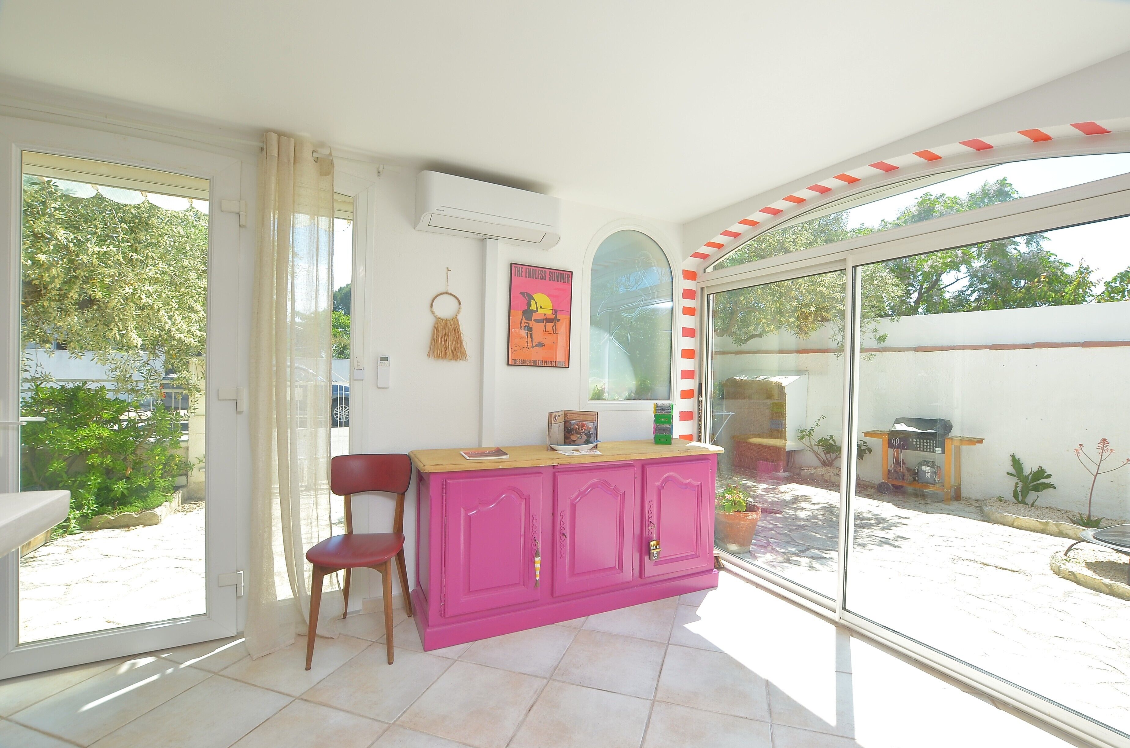 Une pièce avec un meuble rose, une chaise et une affiche accrochée au mur.