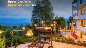 An outdoor seating area with a swing chair, string lights, and a view of a mountain range.