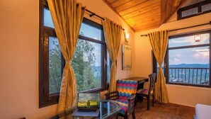 A cozy room with wooden floors, a round glass table, a laptop, and a colorful chair.