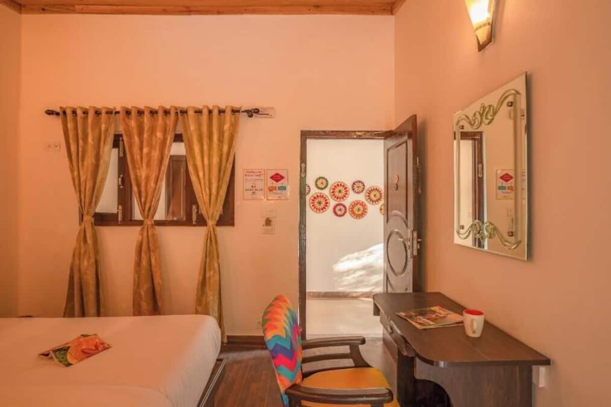 A bedroom with a bed, a desk, a chair, and a door with decorative patterns.