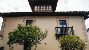 A building with a flat facade, two windows with dark frames, and a small balcony with ornate railings. - Casa Puebla - Cangas de Onís (Cangas de Onís)