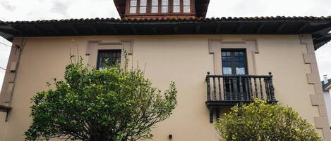 A building with a flat facade, two windows with dark frames, and a small balcony with ornate railings.