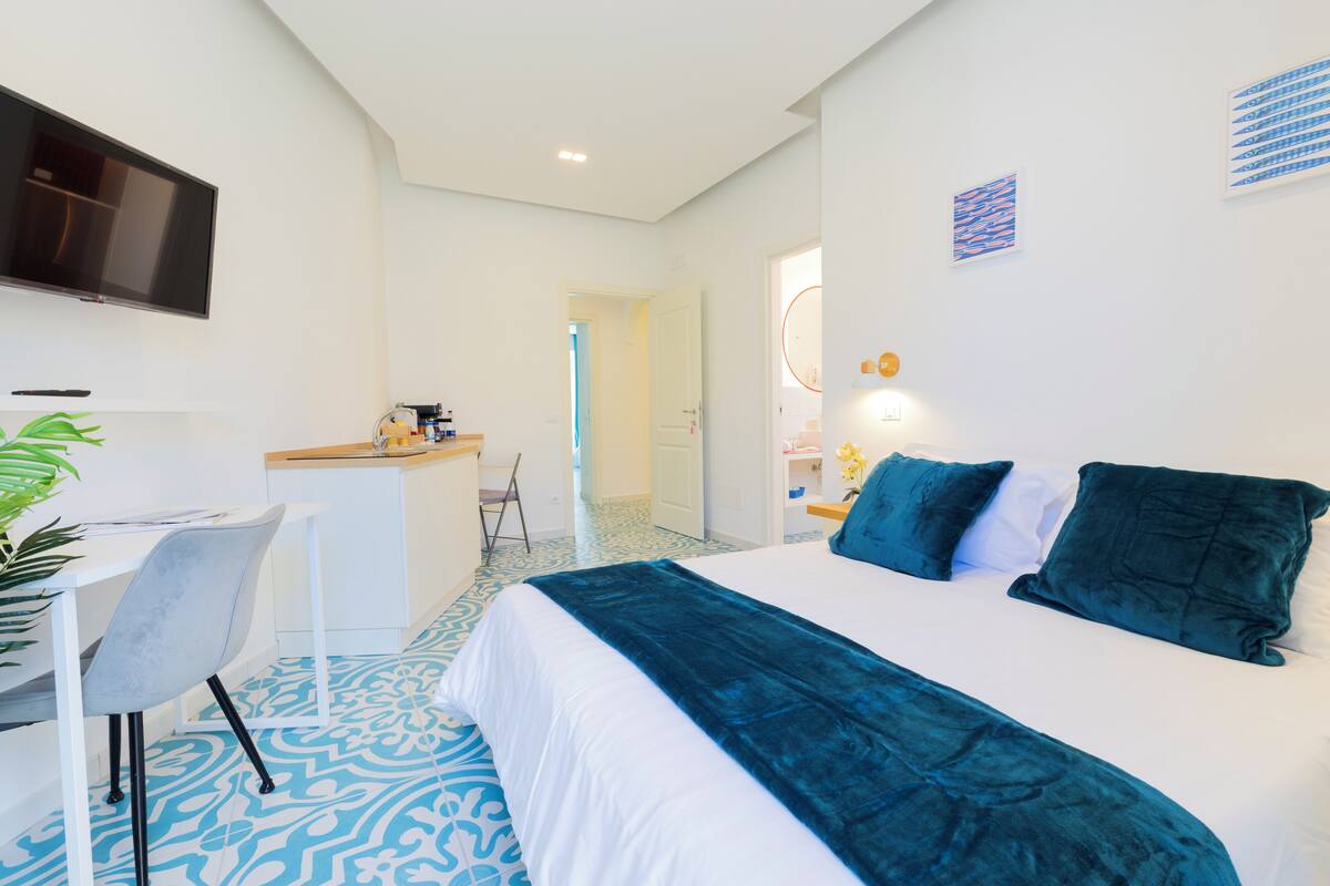 A modern hotel room with a large bed, a desk, and a chair.