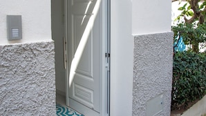A white building with a number 7 sign, a door, and a small step leading to the entrance. - Via Roma Suites (Ischia)