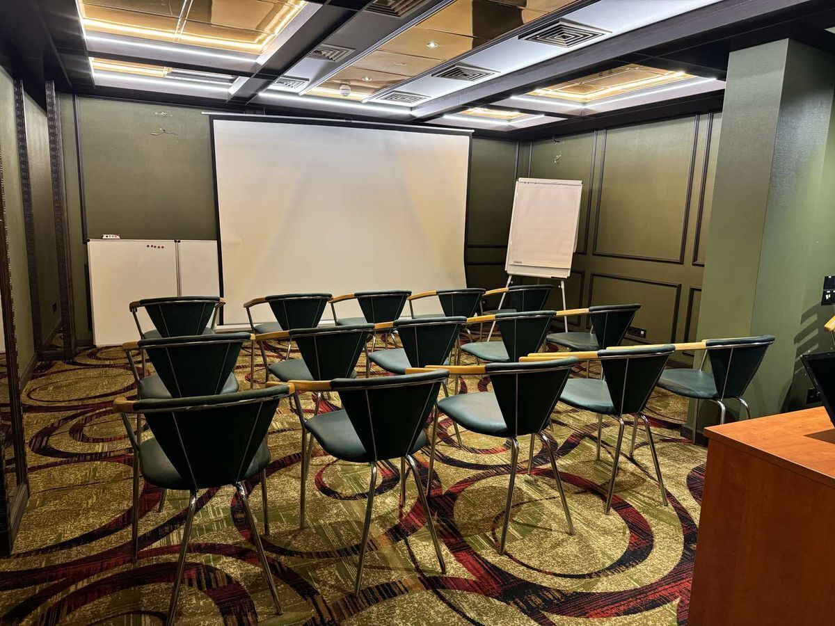 A conference room with rows of chairs, a whiteboard, and a carpeted floor.
