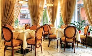 Formal dining area with round tables, upholstered chairs, and elegant drapes.
