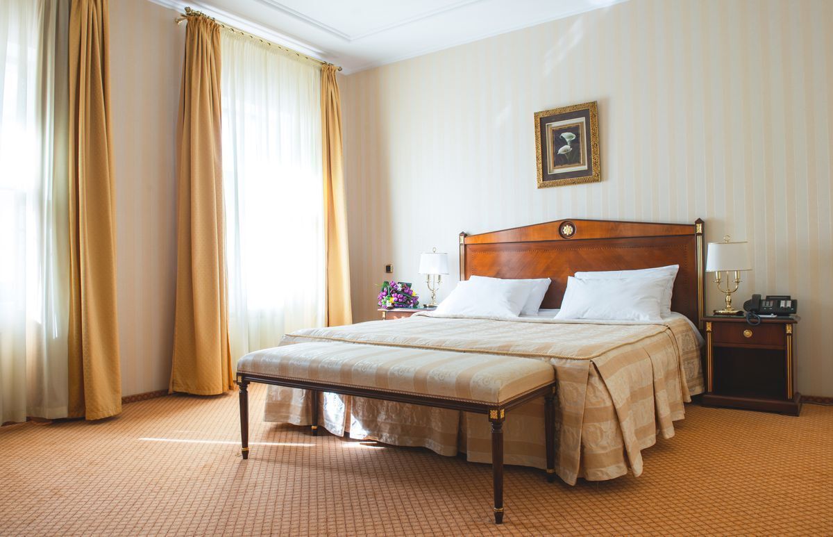 A hotel room with a large bed, a nightstand, a lamp, and a framed picture on the wall.