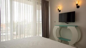 A hotel room with a bed, a TV mounted on a wall, and a window with curtains. - The Moon Villas (Vama Veche)