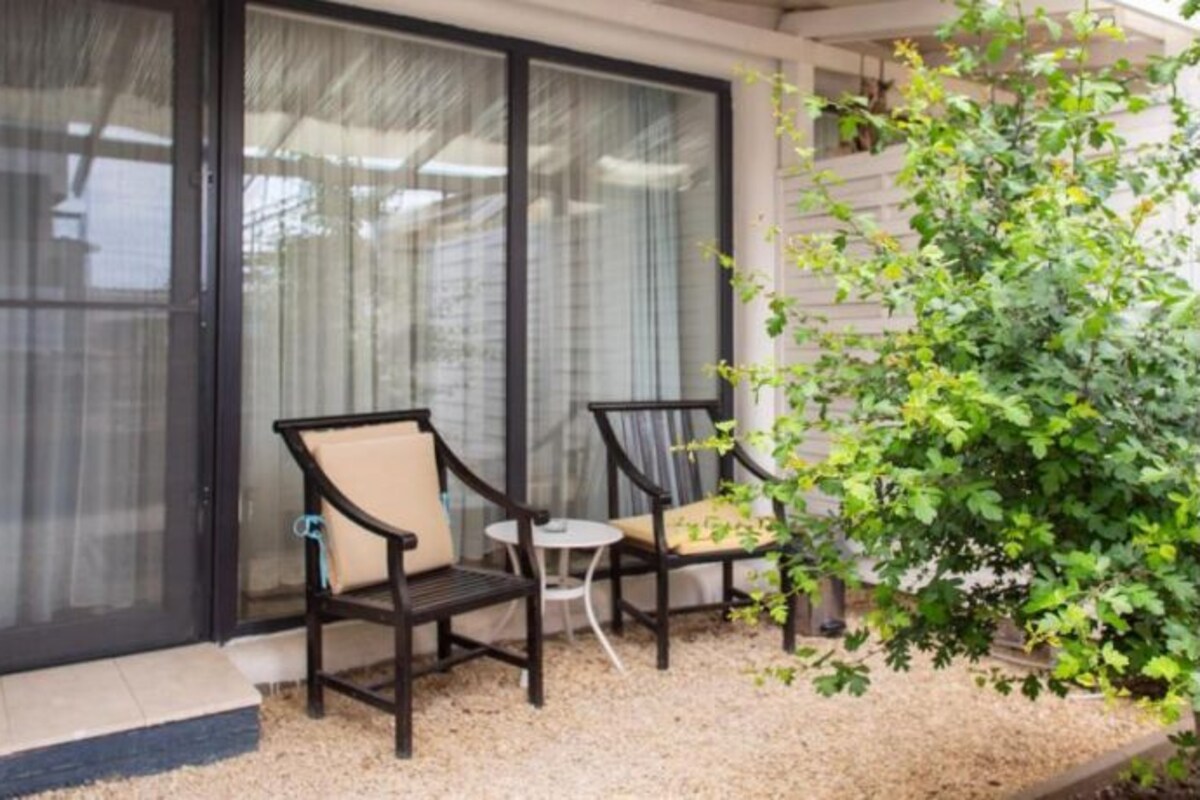 A patio area with two chairs and a small table, a sliding glass door, and a potted plant.