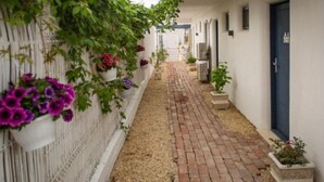 A narrow corridor with a brick floor, white walls, and potted plants. - The Moon Villas (Vama Veche)