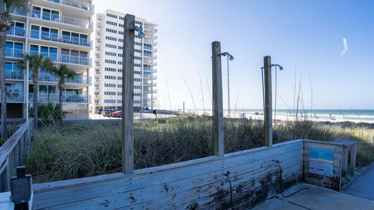 A wooden boardwalk leading to a beach with a high-rise building in the background.