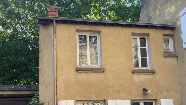A two-story building with a beige facade, white shutters, and a brick chimney. There are potted plants in front of the building. - Lodging for the 24h of Le Mans week in the historic city center. (Le Mans)