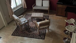 A dining area with a table and chairs, a sofa, a patterned rug, and a window with curtains. - Lodging for the 24h of Le Mans week in the historic city center. (Le Mans)