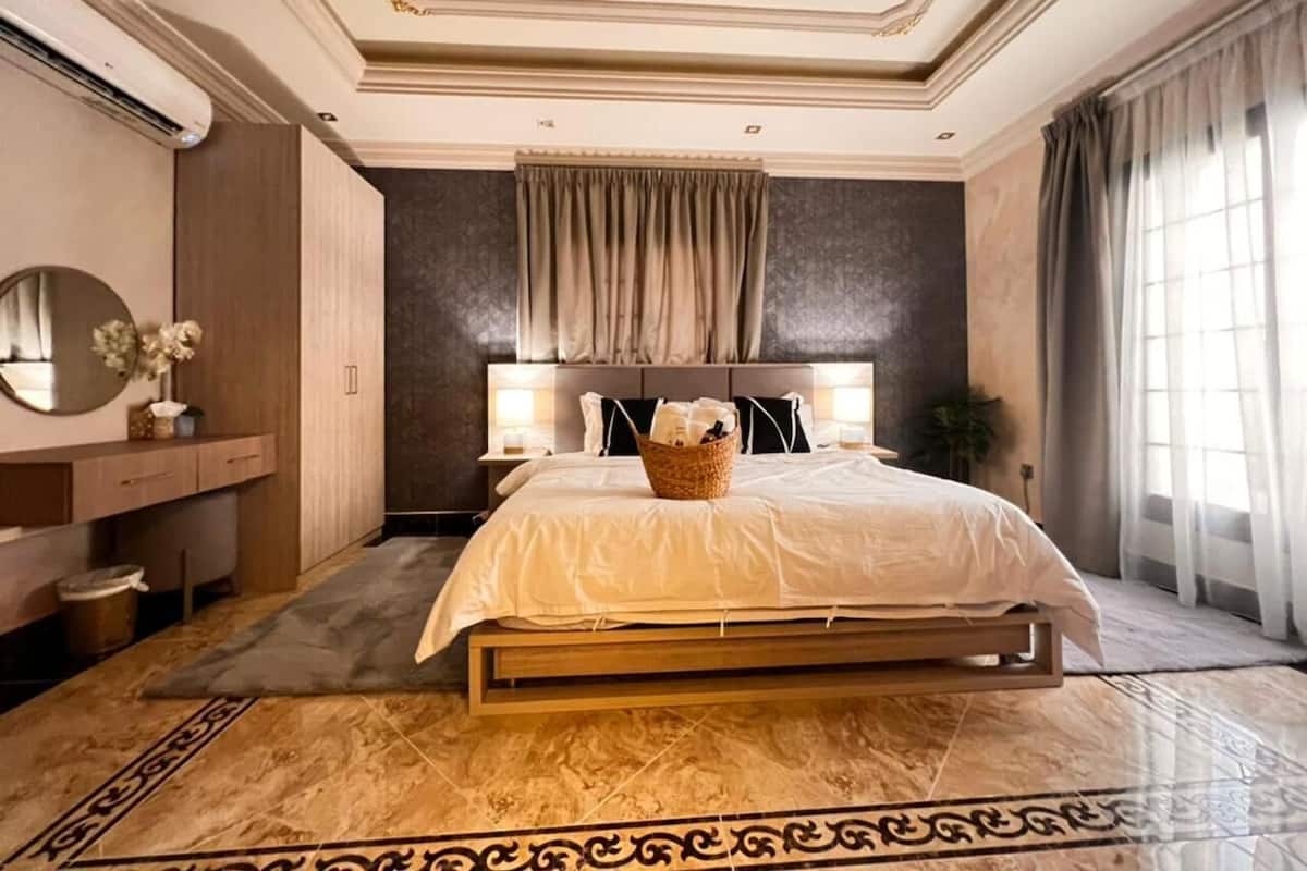 A spacious bedroom with a large bed, a bedside table, a mirror, and a nightstand.