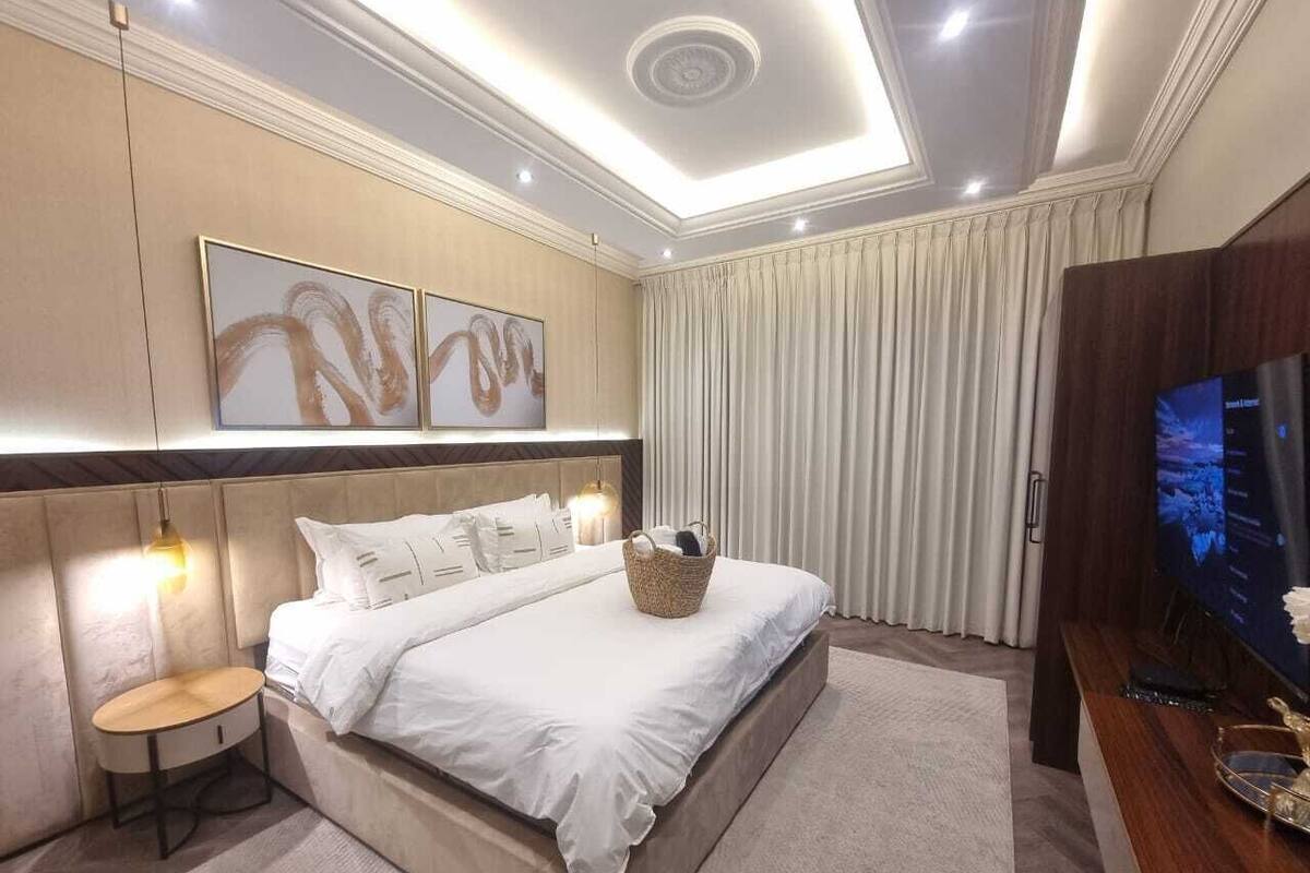 A modern hotel room with a large bed, a flat-screen TV, and a ceiling light fixture.