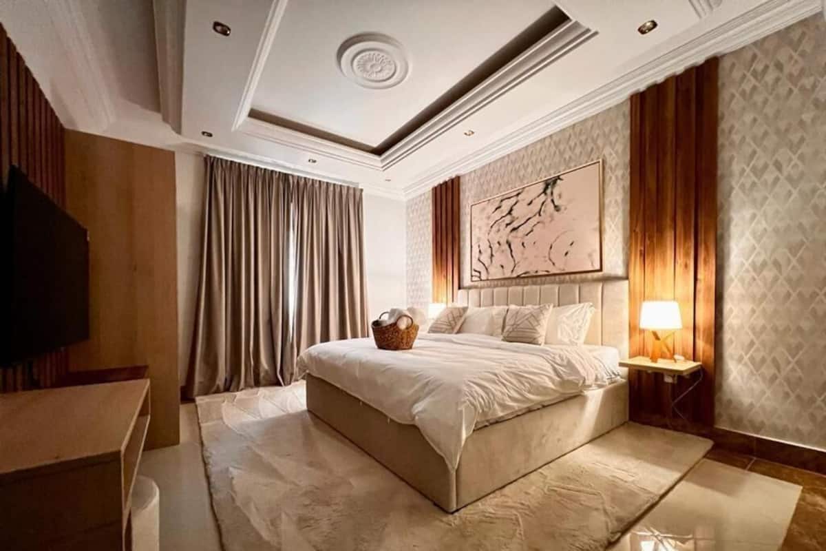A hotel room with a large bed, a television, a desk, and a wall-mounted artwork.