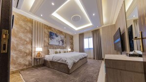 A modern hotel room with a large bed, a flat-screen TV, a vanity with a mirror, and a large window with curtains. - Hometel Khozama Jed (Jeddah)