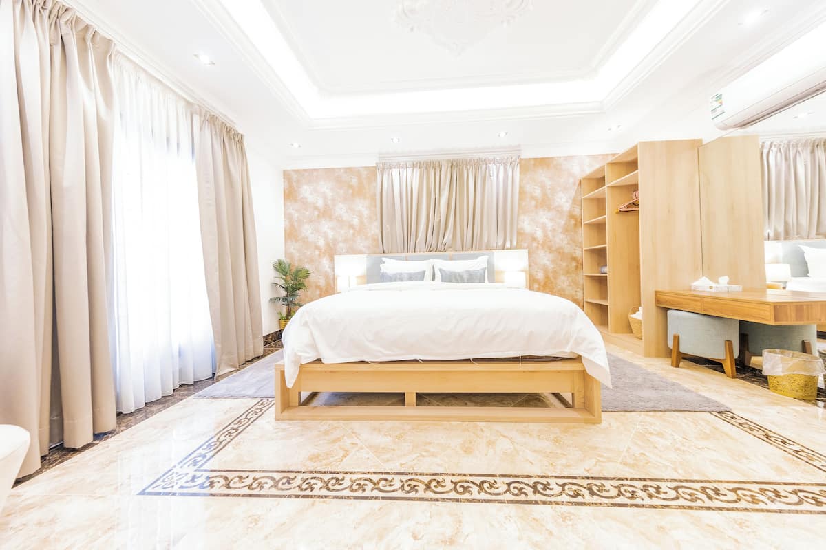 A spacious bedroom with a large bed, wooden wardrobe, and a desk area.
