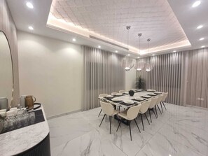 A modern conference room with a marble floor, a long table with chairs, and pendant lighting. - Hometel Khozama Jed (Jeddah)