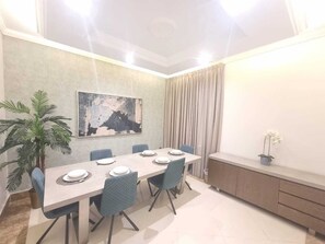 A dining area with a long table, chairs, and a potted plant. - Hometel Khozama Jed (Jeddah)