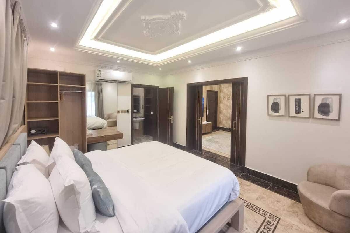 A bedroom with a large bed, a wardrobe, a mirror, and a bathroom visible through an open door.