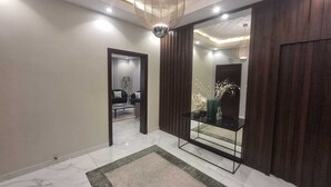 A modern hallway with a marble floor, a glass coffee table, a dark wooden door, and a hanging light fixture. - Hometel Khozama Jed (Jeddah)