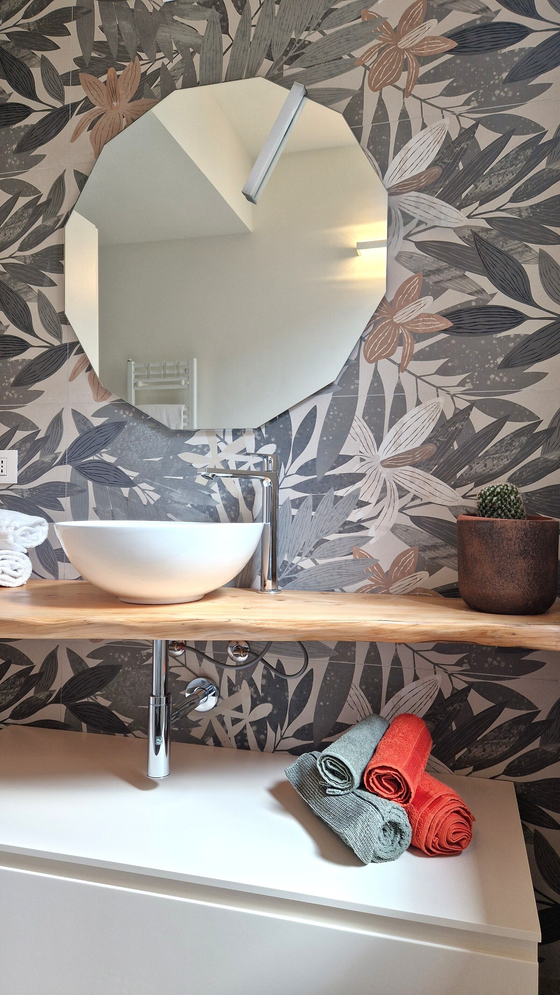 A bathroom with a white sink, a large mirror, and a potted cactus.