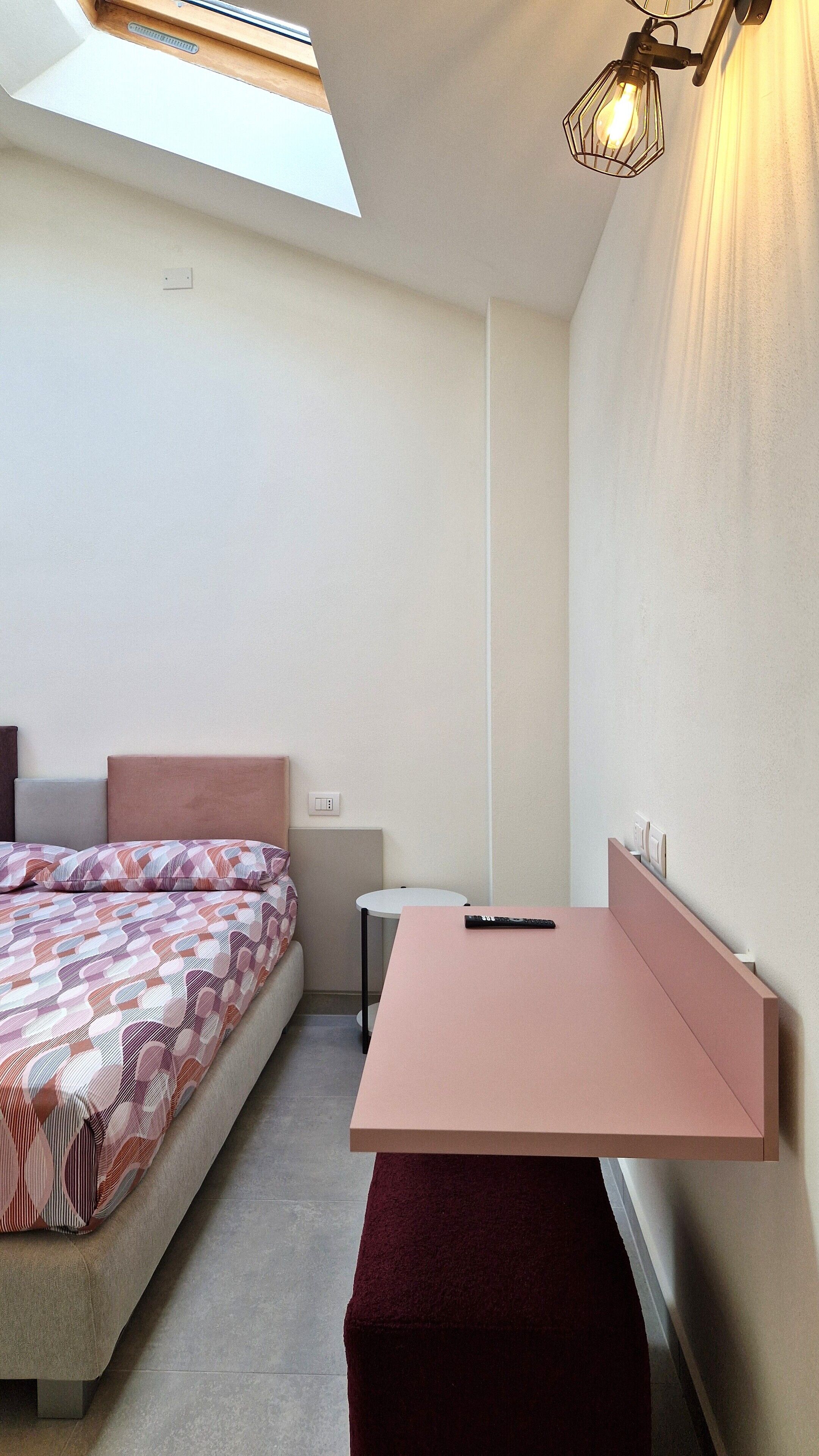 Un dormitorio pequeño y moderno con una cama, un escritorio y un banco.